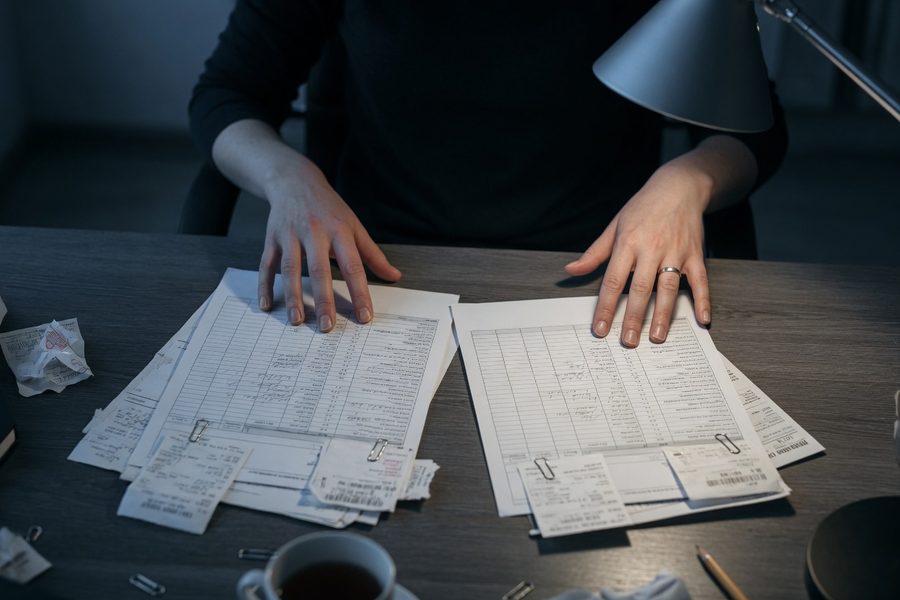 A 30-year-old reviewing bank statements on a laptop, circling recurring expenses.