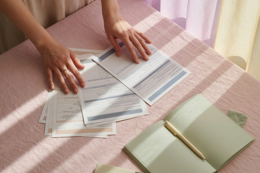 A beginner sits at a kitchen table reviewing bank statements with highlighters and a CFPB budget worksheet.