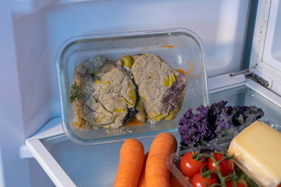 Labeled glass containers of leftovers in a fridge, organized and ready to eat