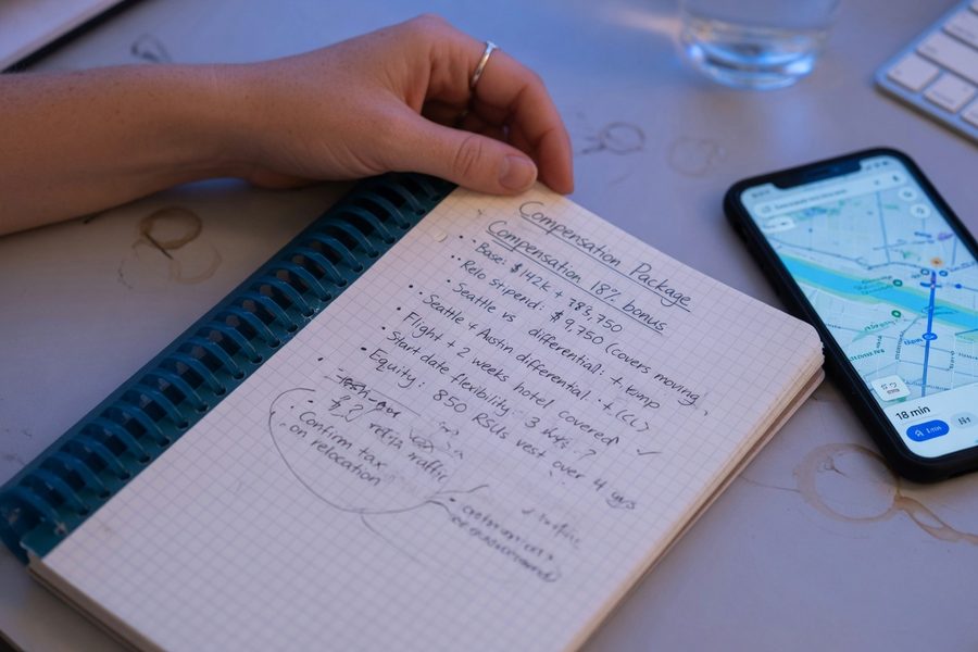 Remote worker reviewing salary and cost-of-living spreadsheet at a home desk in a new city