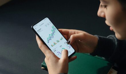 Side-by-side comparison of micro-investing app icons and fee structures on a smartphone screen