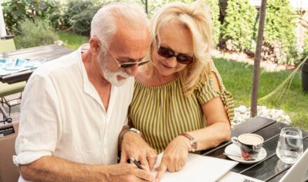 Retired couple reviewing mortgage documents at home with financial statements on table