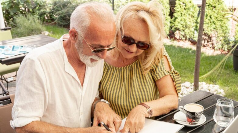 Retired couple reviewing mortgage documents at home with financial statements on table