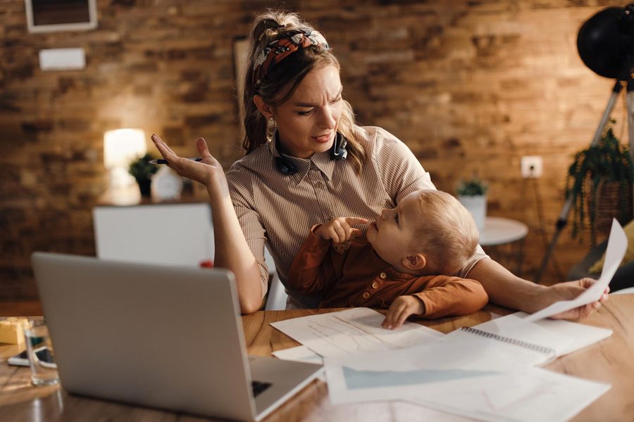 Single mother reviewing tax forms at kitchen table with W-2 and calculator